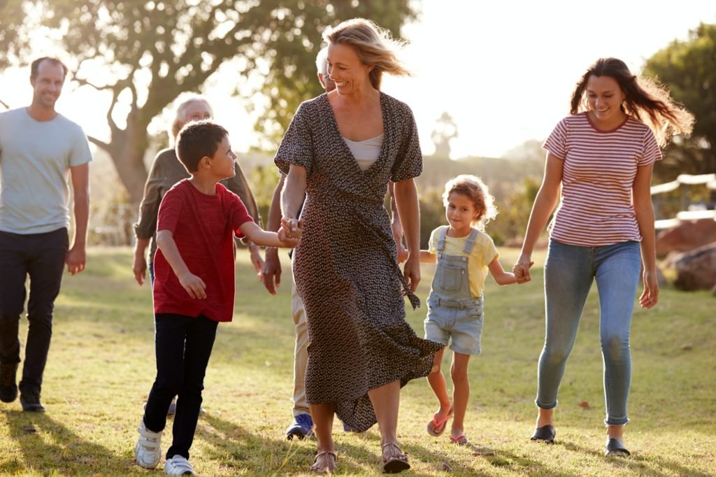 Multi-Generation Family Walking In Countryside Against Flaring Sun